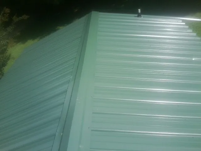 New green metal panels meeting at the ridge of a roof — Flat Roof Repair work by our crew in Pilot