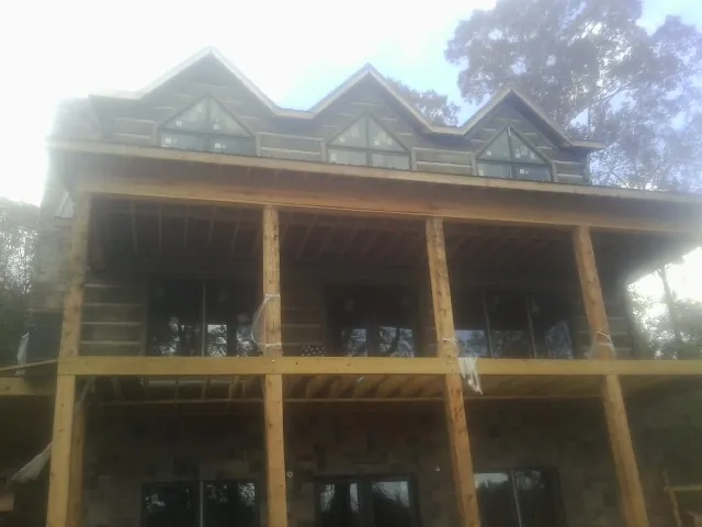 Dormers and porch framing on a large log home under construction — Roof Coating work by our crew in Pilot