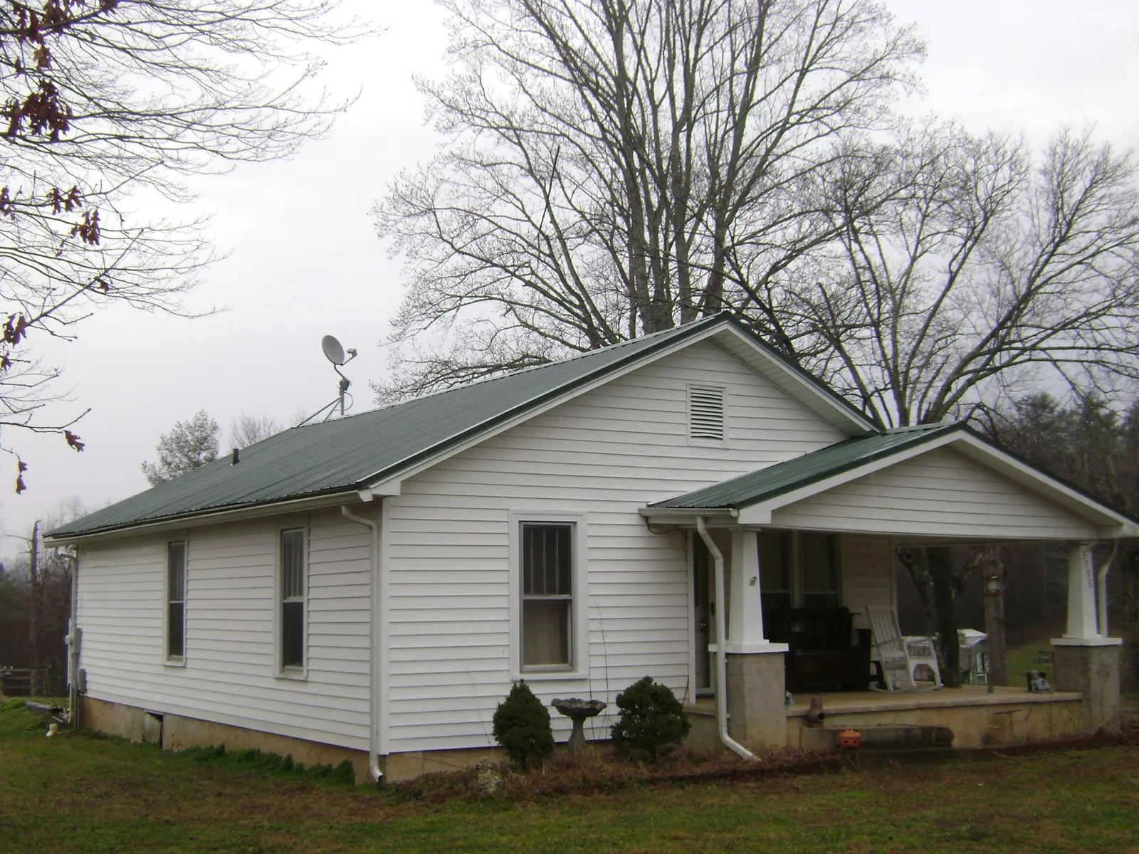 Green metal roof on a white bungalow with a side porch in Pilot
