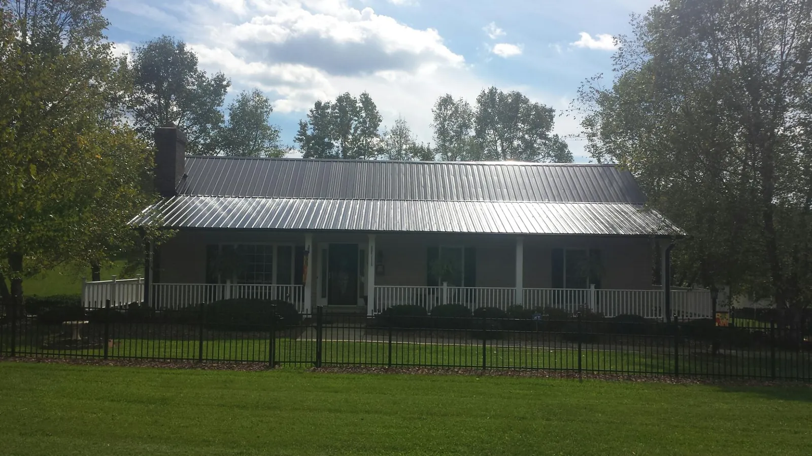 Gray metal roof on a brick ranch with a full width front porch — Gutter Guard Installation work by our crew in Pilot