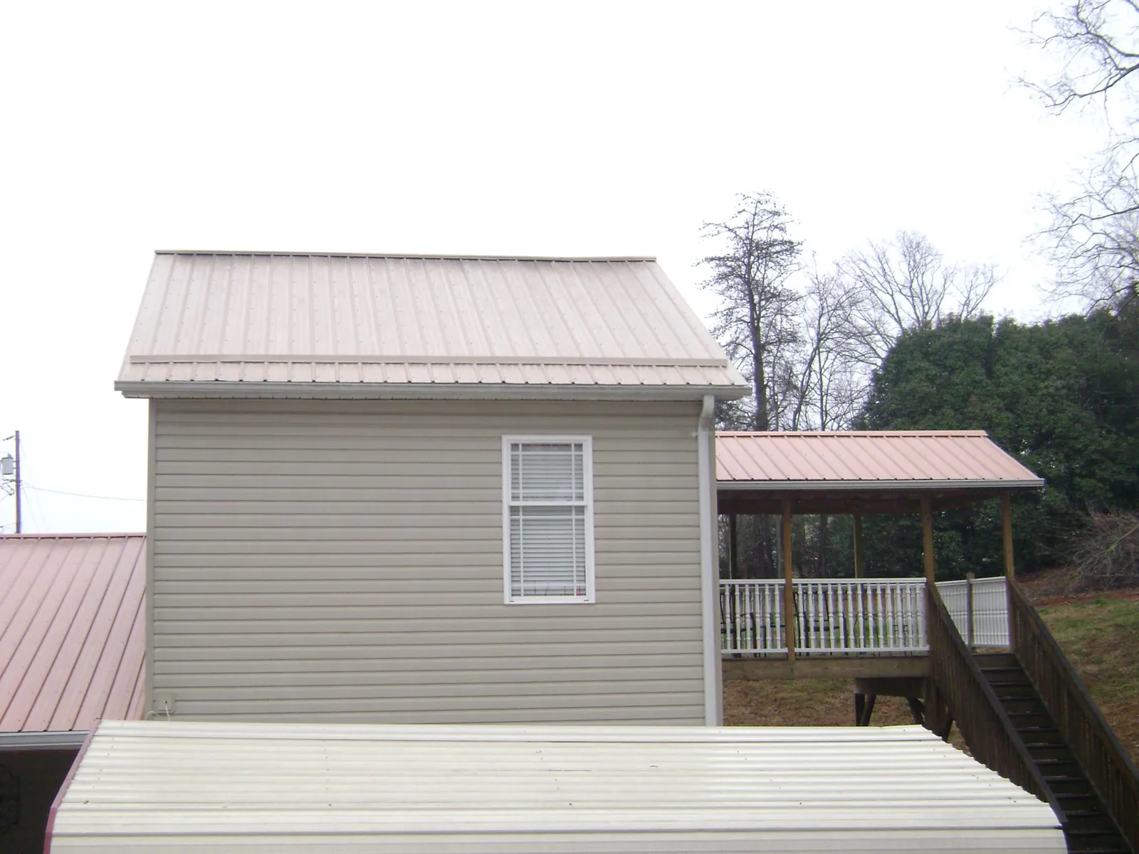 Tan metal roofs on a two story addition and attached porch, from a Roof Replacement job in Pilot
