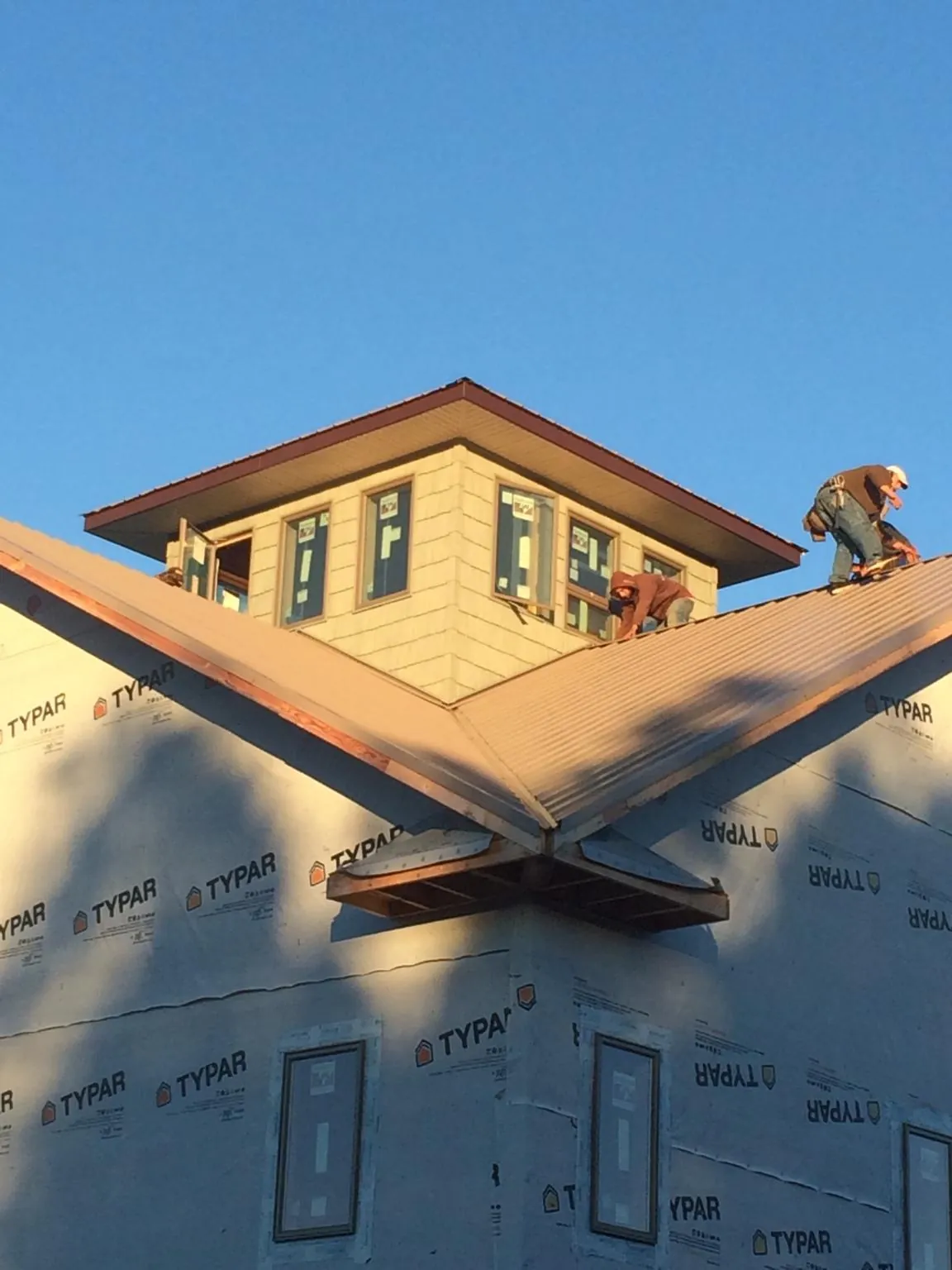 Roofers working around a rooftop cupola on a new metal roof at sunset — Roof Waterproofing in Pilot by Roofing Brothers